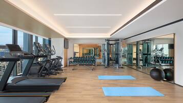 A modern gym with treadmills, weight machines, and yoga mats.