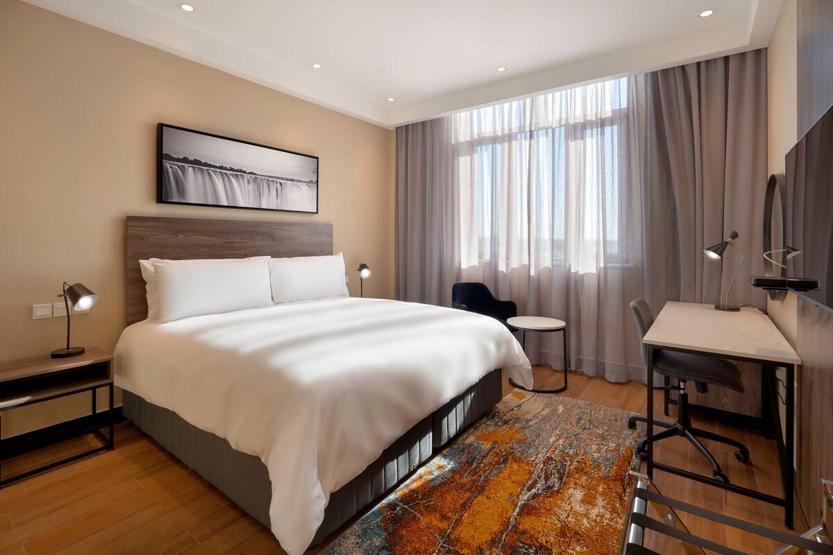 Una habitación de hotel moderna con una cama grande, un escritorio y una silla.