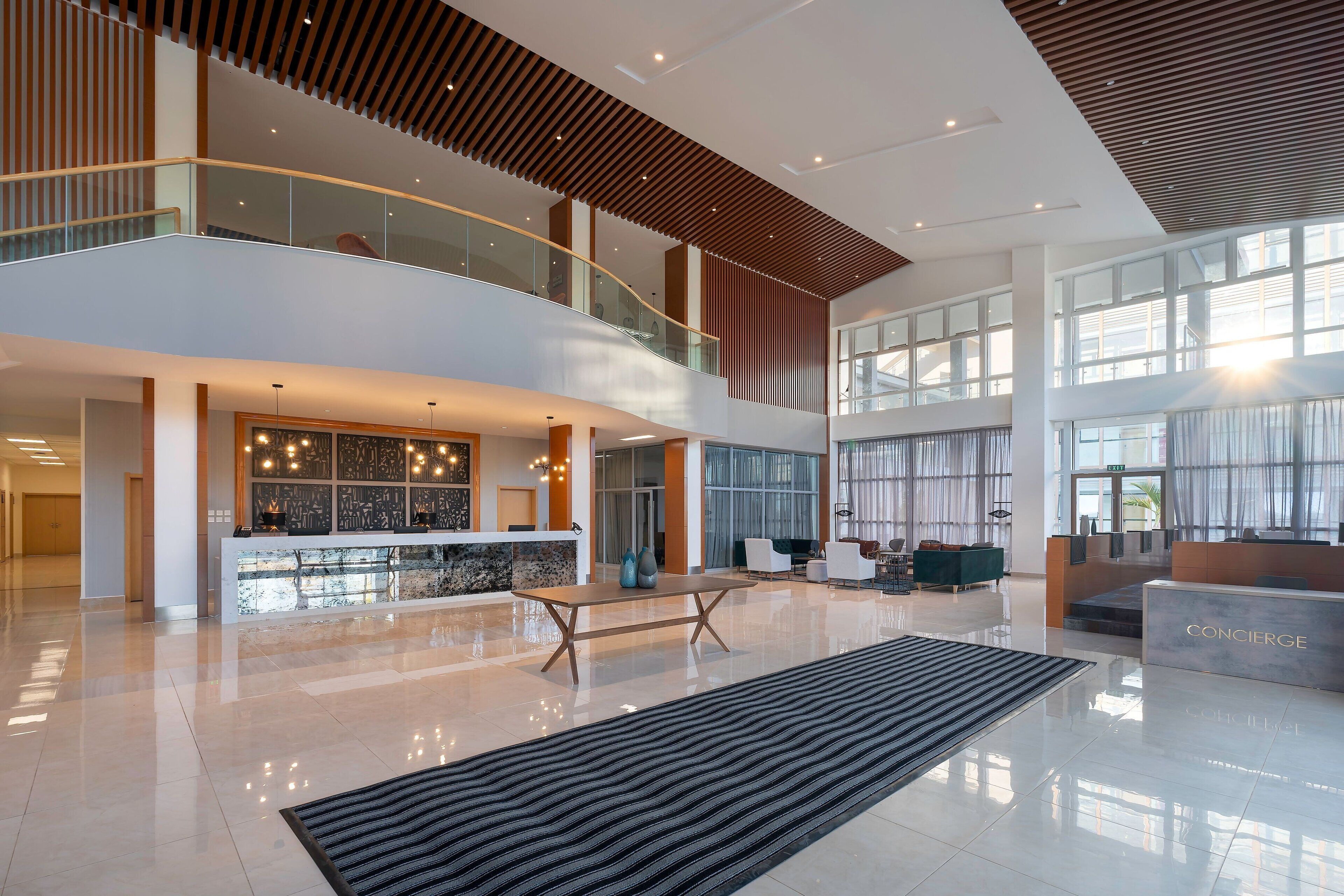 A spacious lobby with a reception desk, seating area, and a staircase connecting two floors.