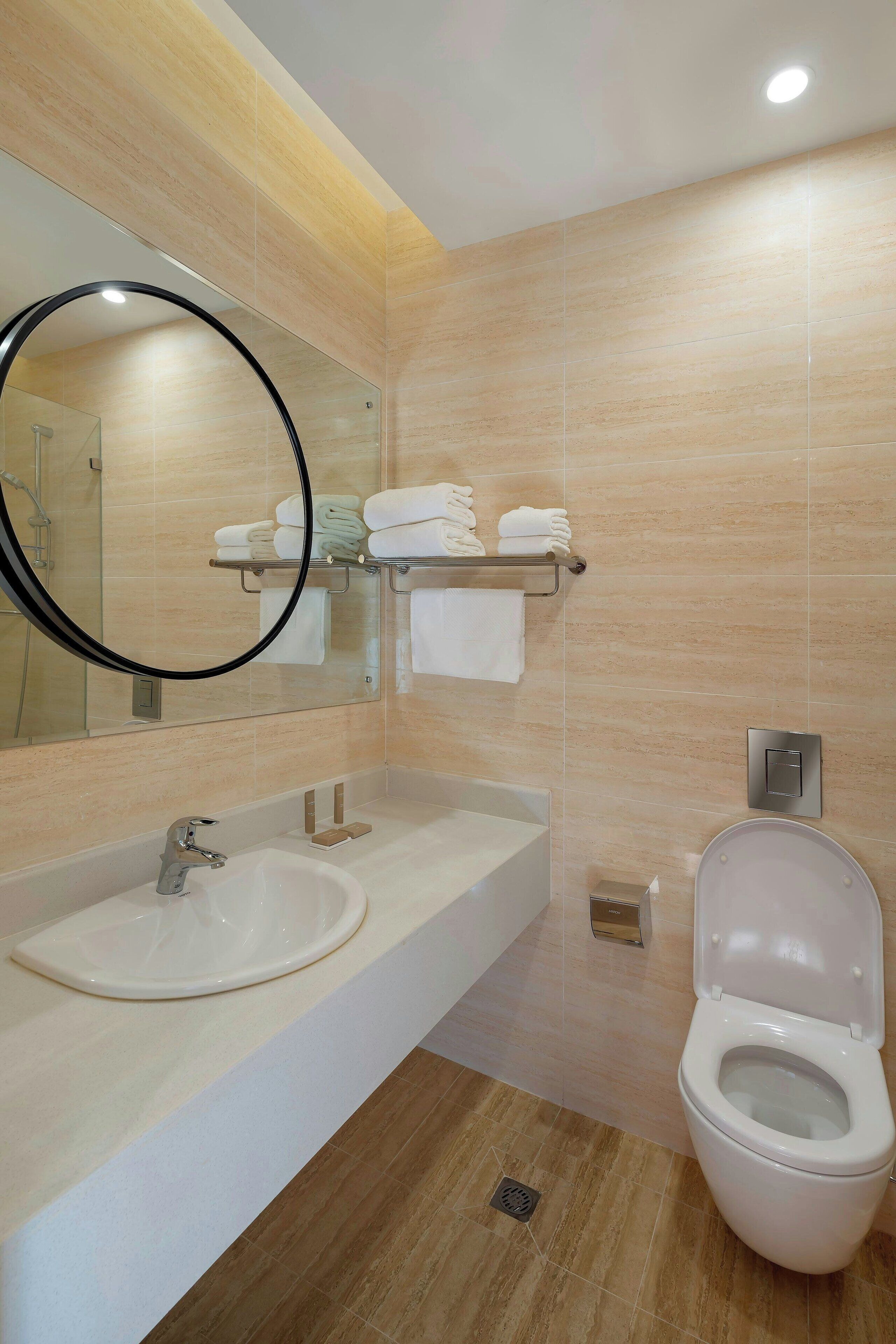 A modern bathroom with a sink, mirror, and toilet.