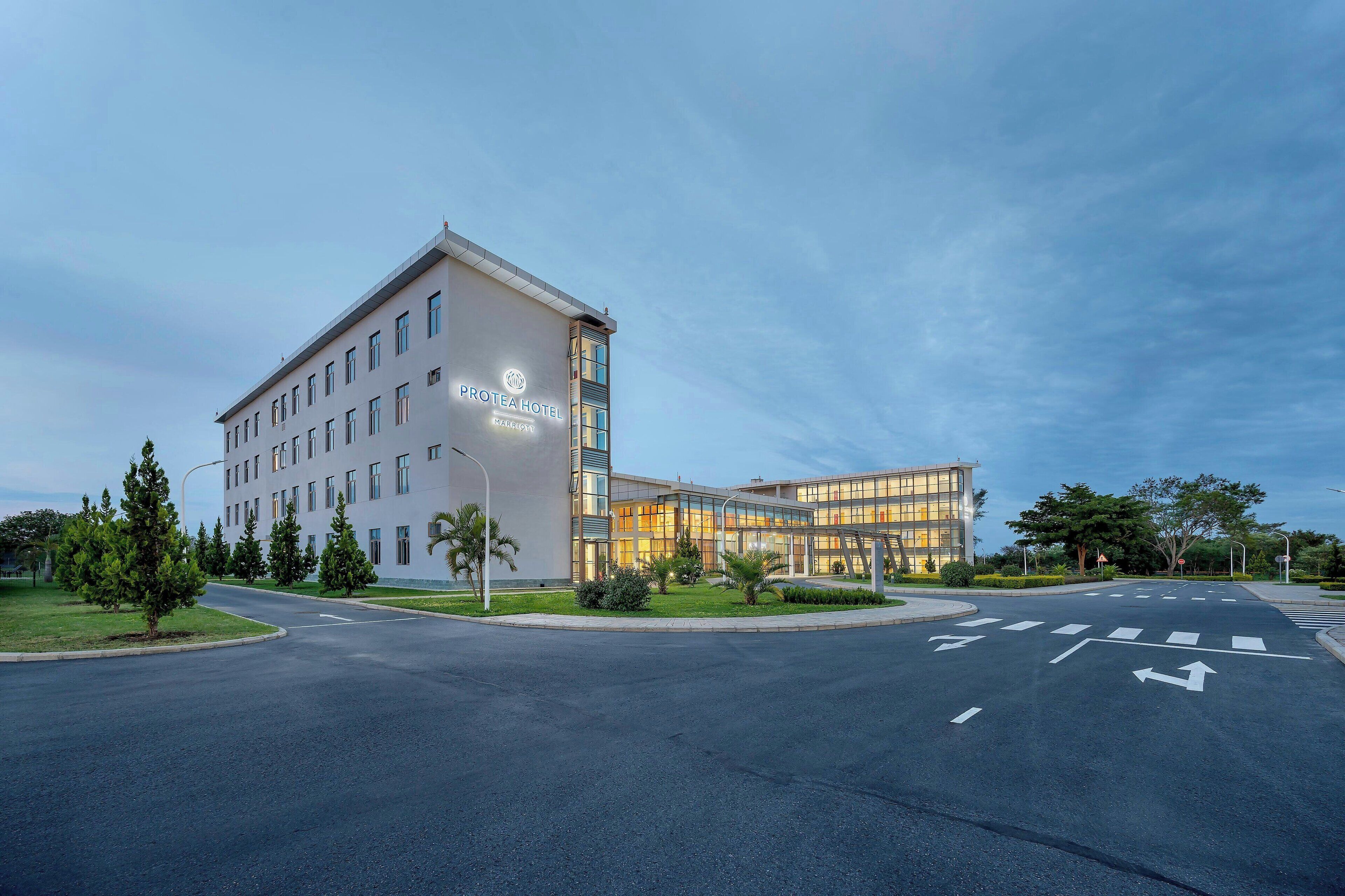A modern hotel building with a prominent sign, a well-maintained parking area, and a landscaped entrance.