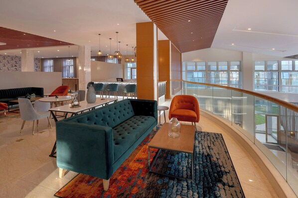 A modern hotel lobby with a blue sofa, a wooden coffee table, and a colorful rug. - Protea Hotel by Marriott Lusaka International Airport (Lusaka)