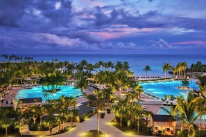 A resort with a large swimming pool, palm trees, and a view of the ocean. - The St. Regis Cap Cana Resort (Punta Cana)