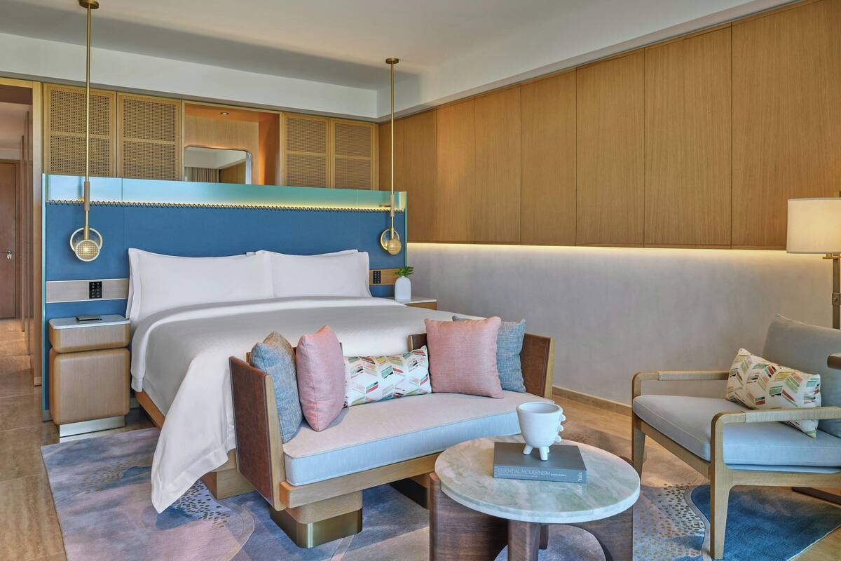 A hotel room with a large bed, a sofa, a small table, and a chair.
