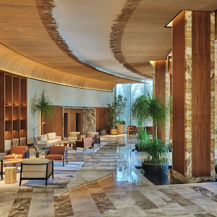 A spacious lobby with a curved ceiling, marble flooring, and multiple seating areas.