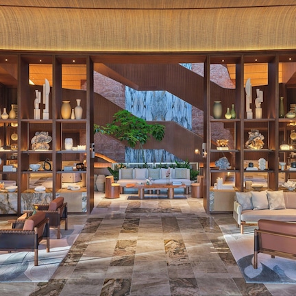 A spacious lobby with a central seating area, a staircase, and a large plant.