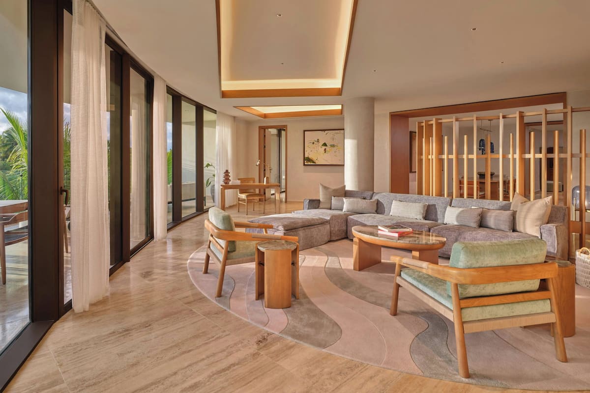 A spacious living room with a large sectional sofa, wooden coffee table, and a glass dining table.