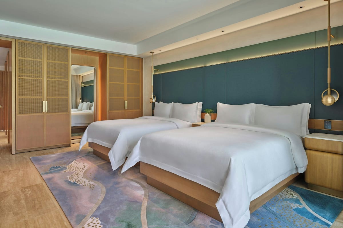 A modern hotel room with two beds, a walk-in closet, and a large mirror.