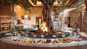 Ein Buffet mit verschiedenen Speisen und ein großer Baum im Hintergrund.