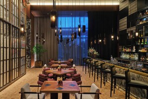 A modern bar area with wooden tables, bar stools, and a well-stocked bar.