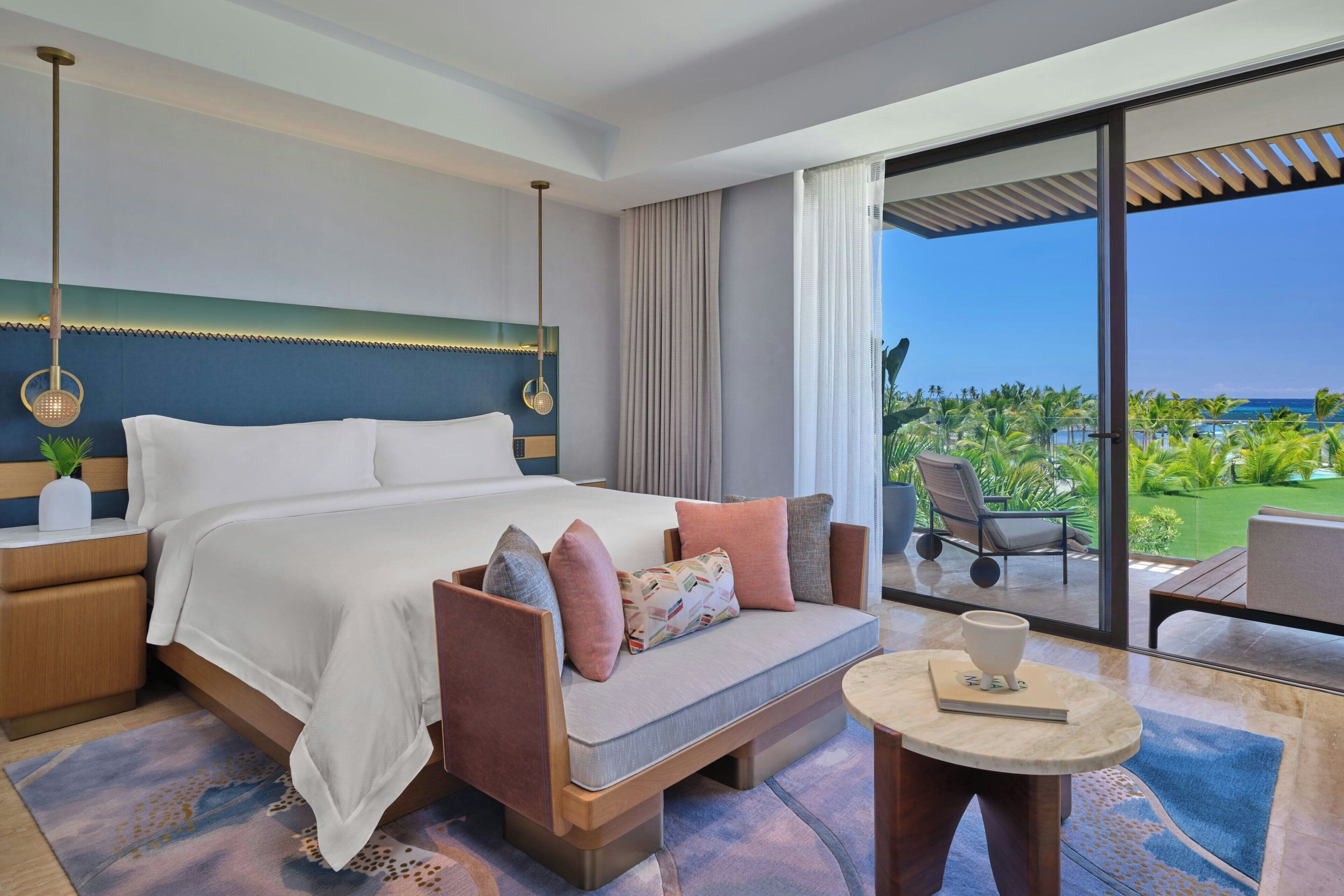 Een moderne hotelkamer met een groot bed, een bank, een klein tafeltje en uitzicht op de oceaan.