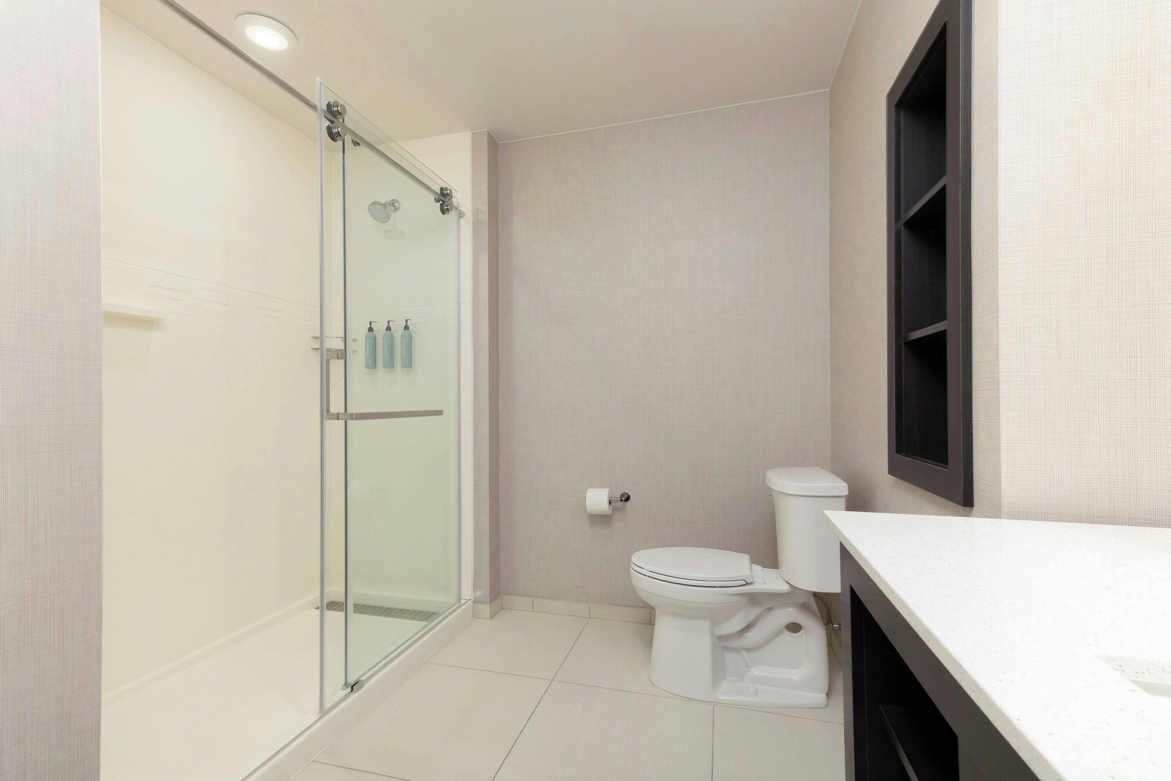 A modern bathroom with a glass-enclosed shower, a toilet, and a white sink.