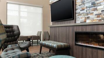 Una sala de estar moderna con chimenea, un televisor de pantalla plana montado en una pared de piedra y asientos cómodos.