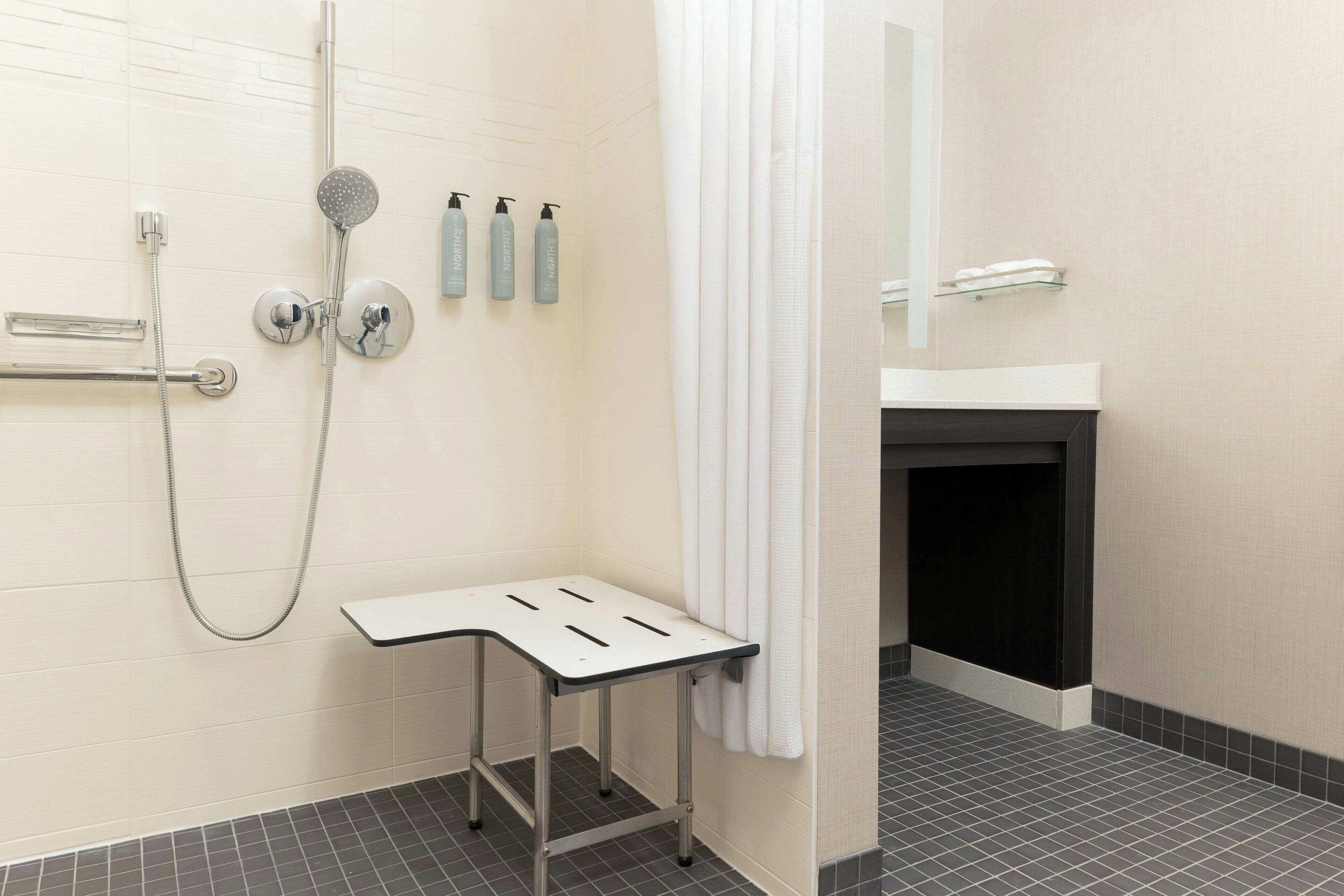 Une salle de bain moderne avec une douche, une petite table et un miroir.
