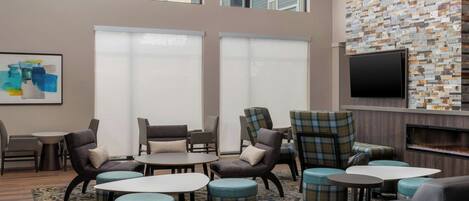 A modern lounge area with comfortable seating, a flat-screen TV, and large windows offering views of the outside.