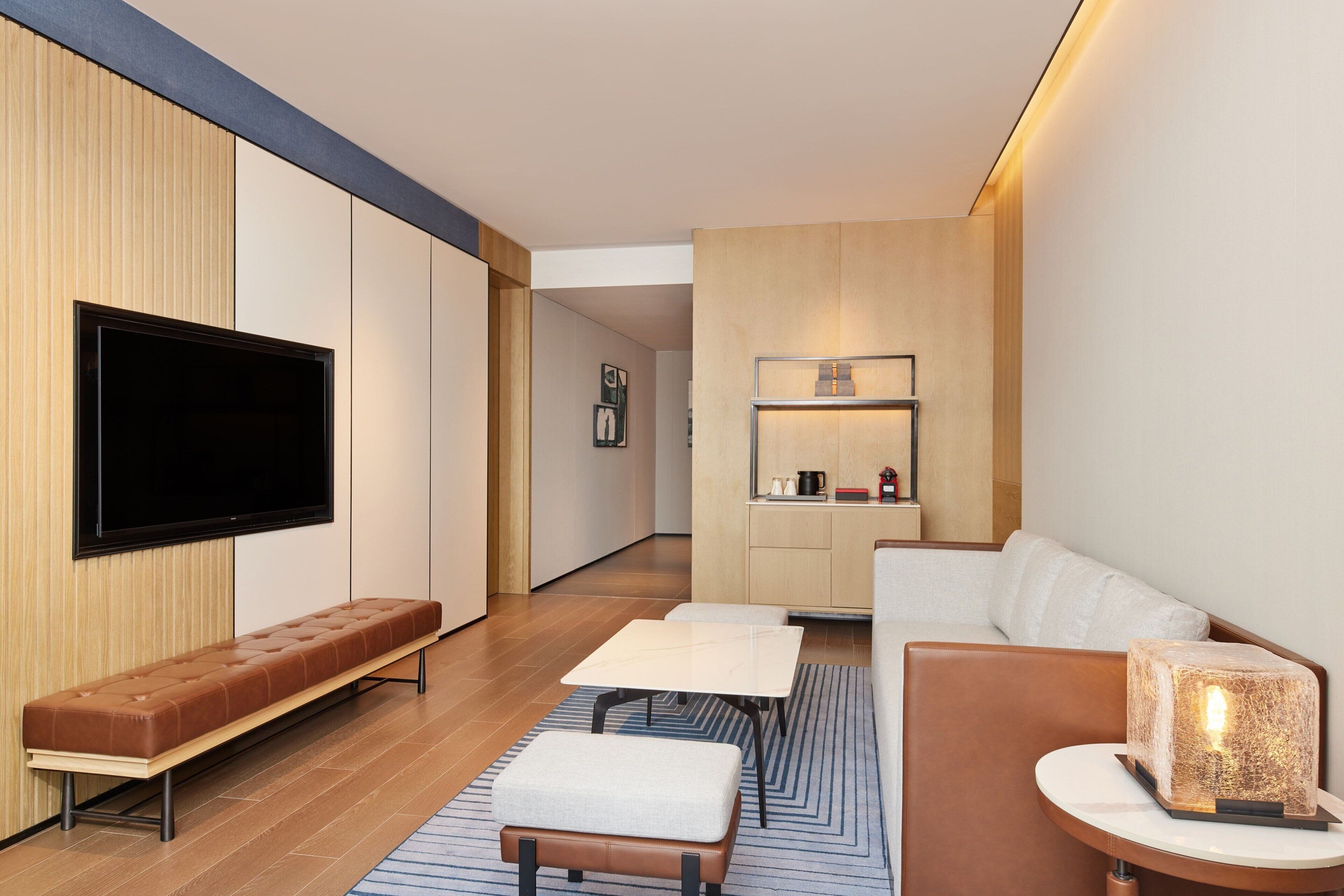 A modern living room with a flat-screen TV, a sofa, a bench, and a coffee table.