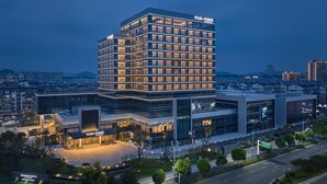 Un hotel moderno con un llamativo letrero de 'Four Points', varios pisos y un área de entrada bien iluminada.