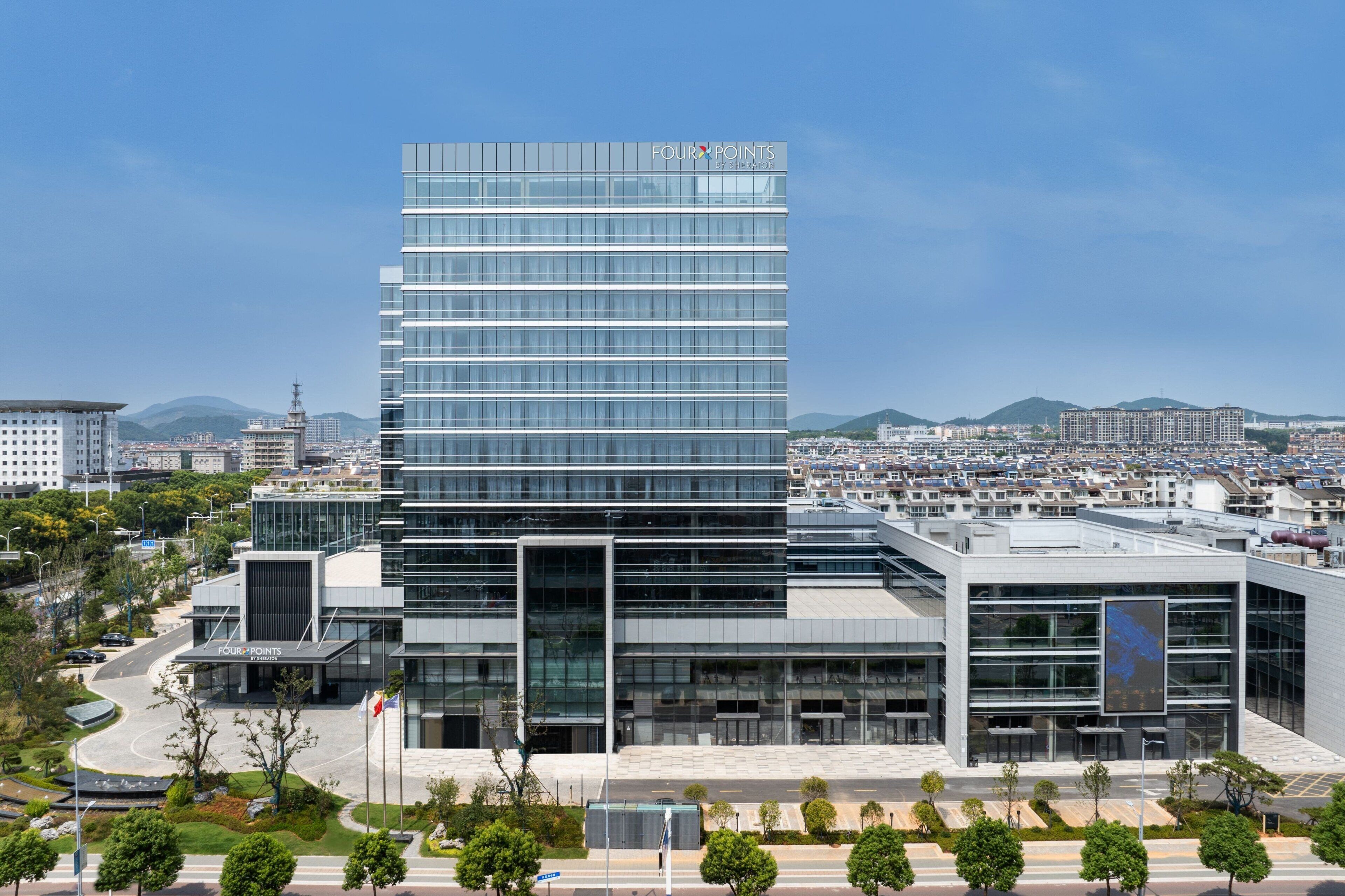 Un edificio moderno con fachada de vidrio y el nombre "FOUR POINTS" en la parte superior.