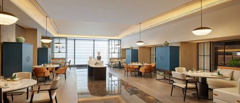 A spacious hotel lobby with multiple dining areas, large windows, and modern lighting fixtures.