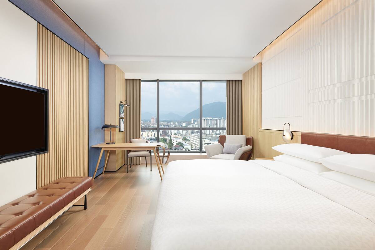 Una habitación de hotel moderna con una cama grande, un escritorio y un televisor.