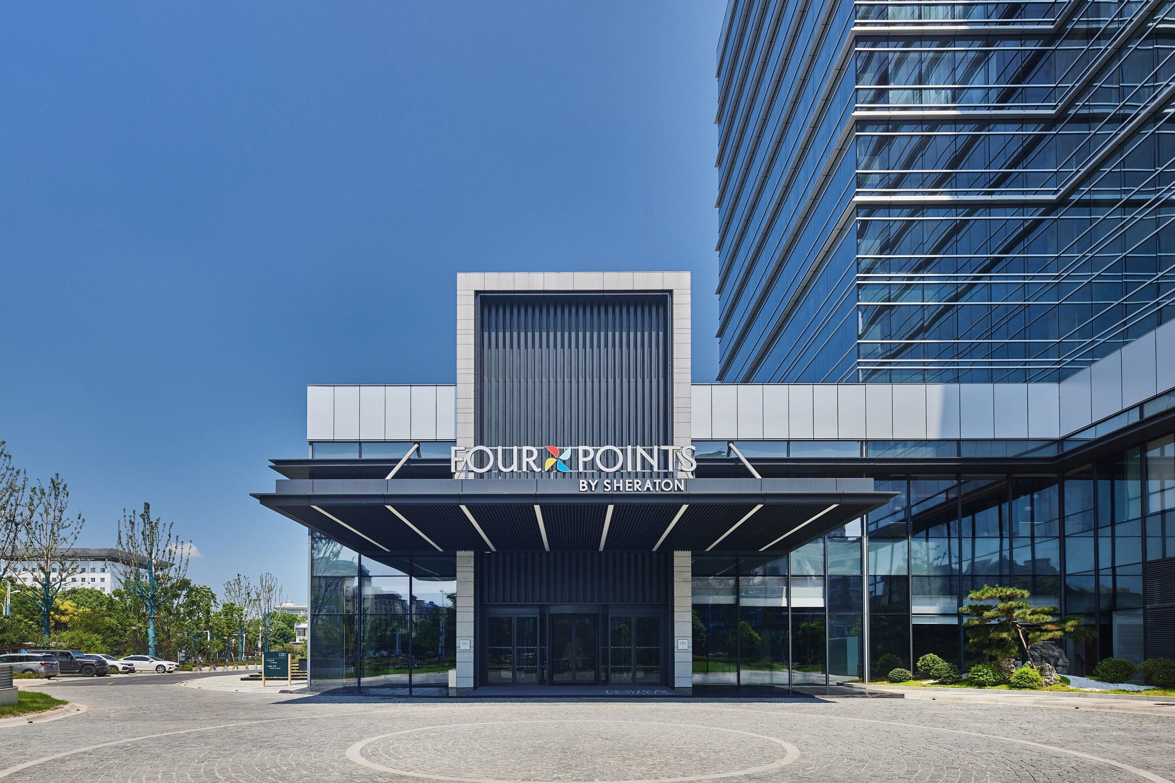 Un bâtiment moderne avec une façade en verre et une enseigne indiquant « FOUR POINTS BY SHERATON ».