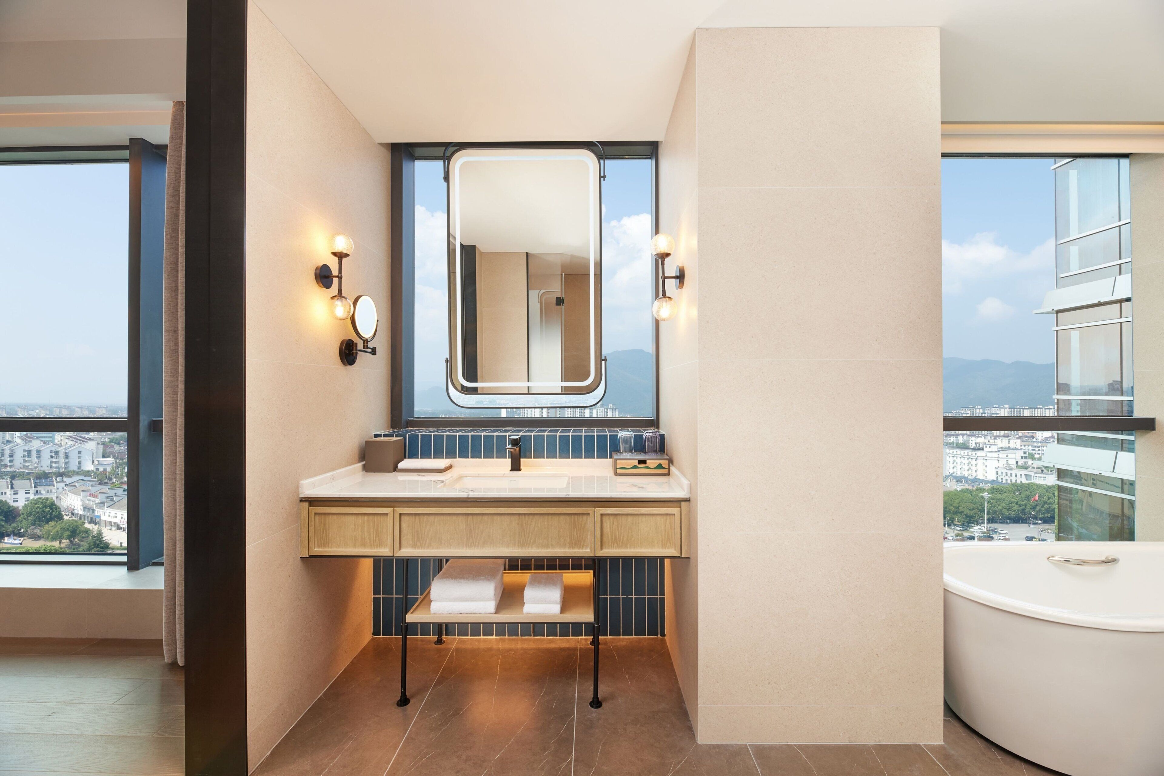 A modern bathroom with a large mirror, dual sinks, a vanity, and a bathtub.