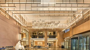 Un hall amplio con una lámpara moderna, un mostrador de recepción y una zona de estar.