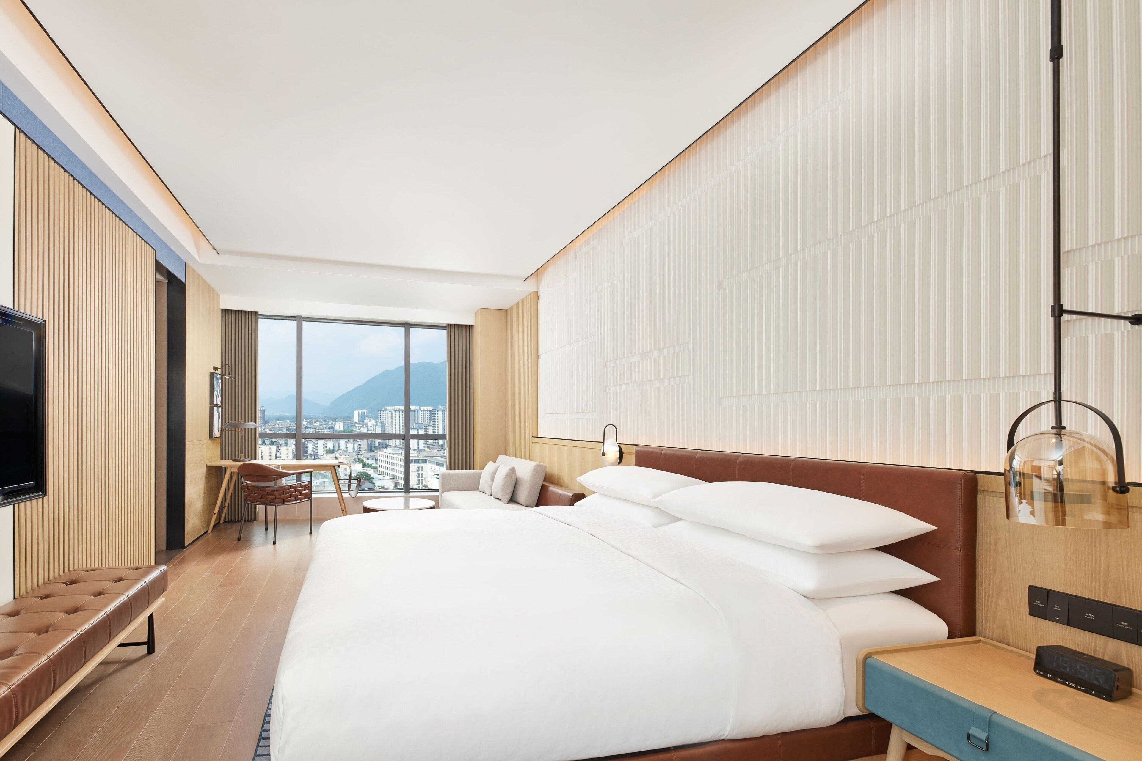 A modern hotel room with a large bed, a desk, and a television.