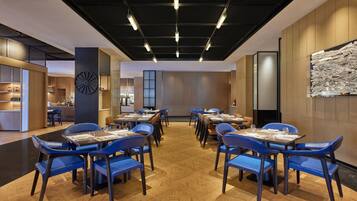 Un comedor moderno con suelo de madera, sillas azules y mesas dispuestas para comer.