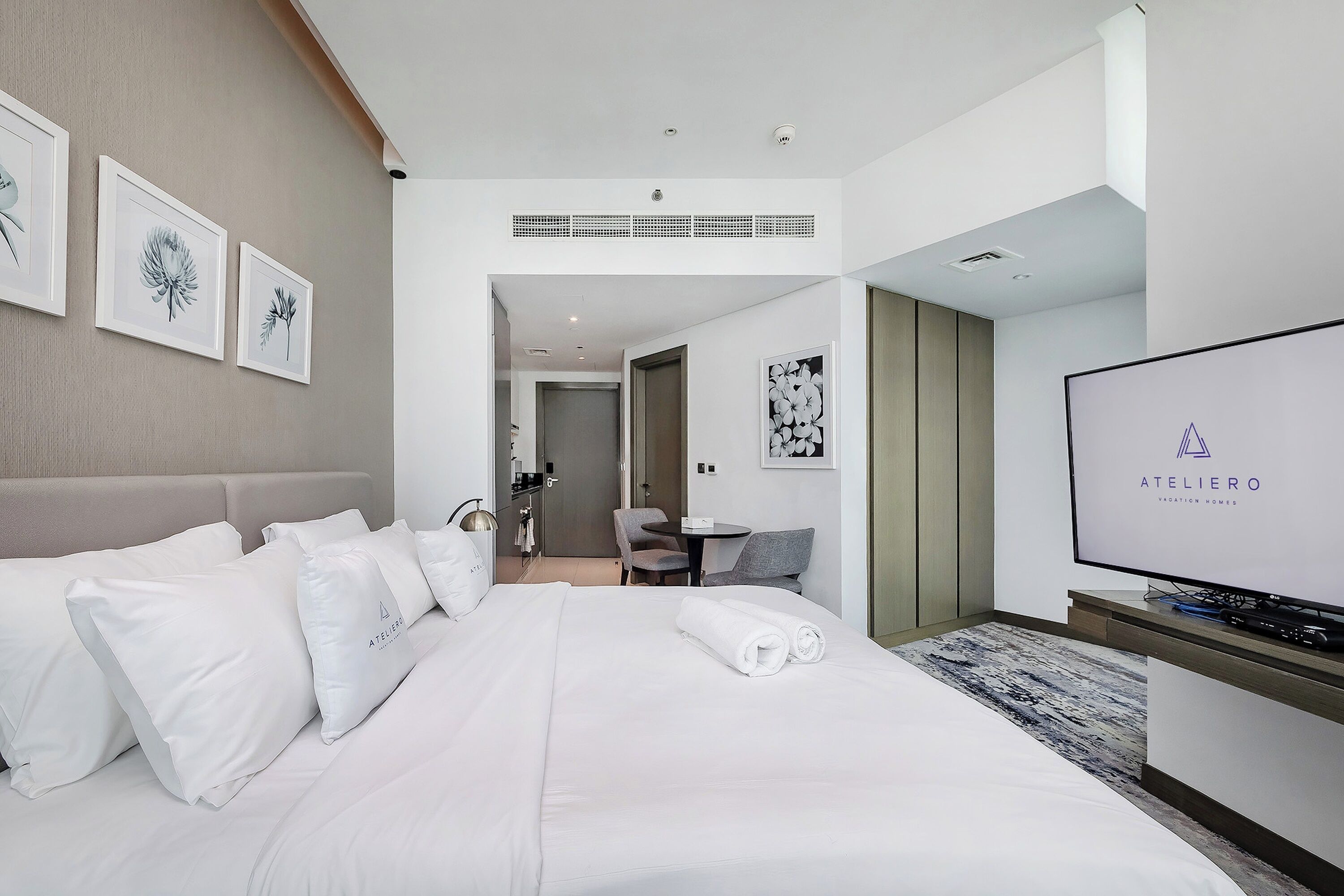Une chambre d’hôtel avec un grand lit, une télévision et des œuvres d’art encadrées accrochées au mur.
