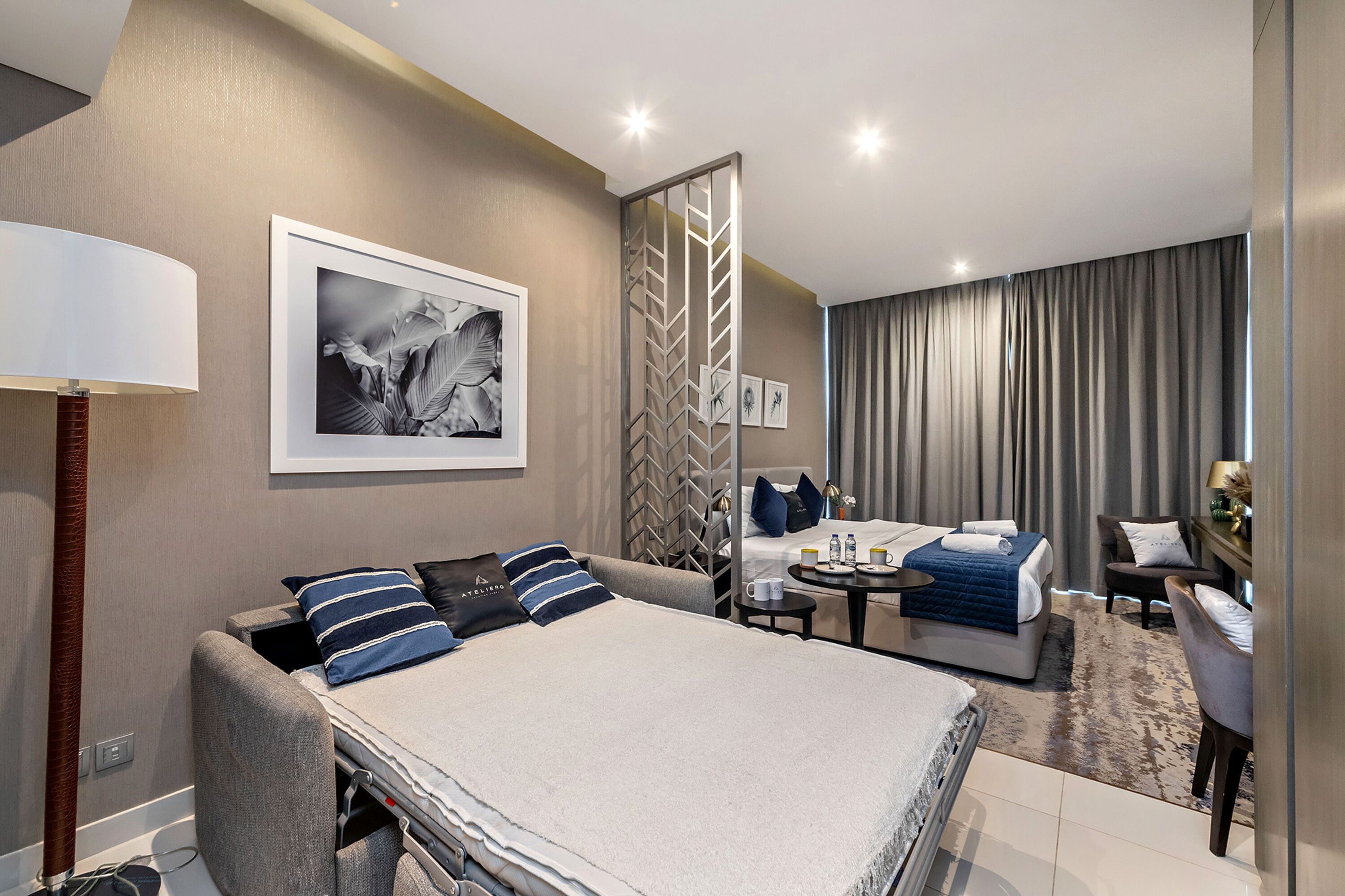 Una habitación de hotel moderna con una cama grande, un sofá, una mesita y una zona de estar separada.