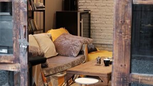A cozy room with a sofa, a coffee table, and a bookshelf. - FullMoon Inn (Lijiang)