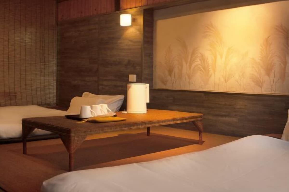 A hotel room with a bed, a small table with a lamp, and a painting on the wall.