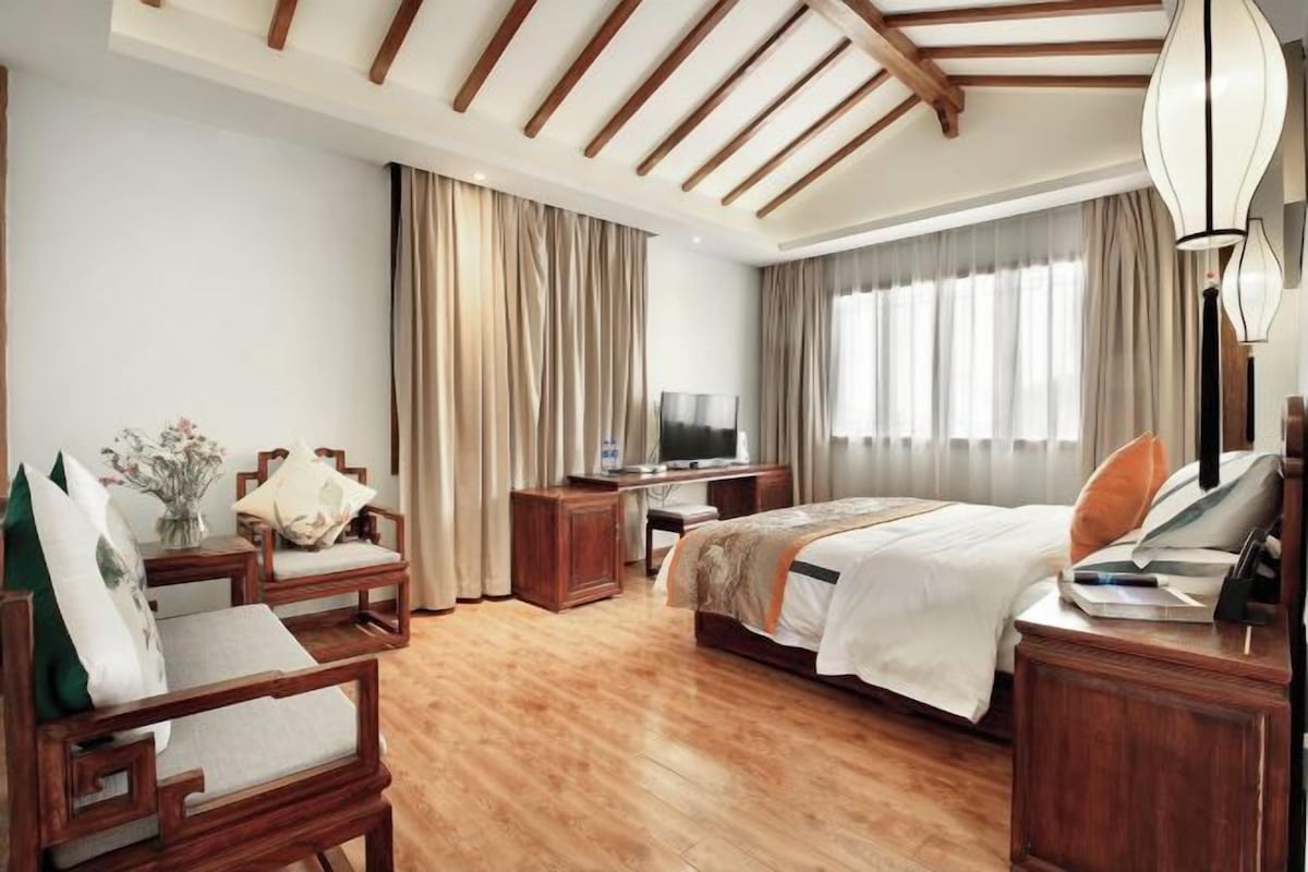 Una habitación de hotel con una cama, un escritorio, una silla, un televisor y una lámpara.