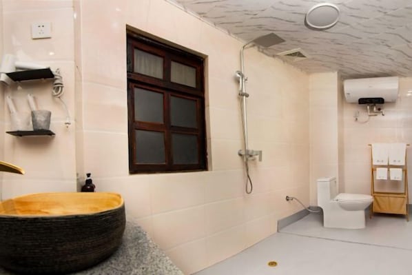A bathroom with a large round basin, a shower, a toilet, and a window. - FullMoon Inn (Lijiang)