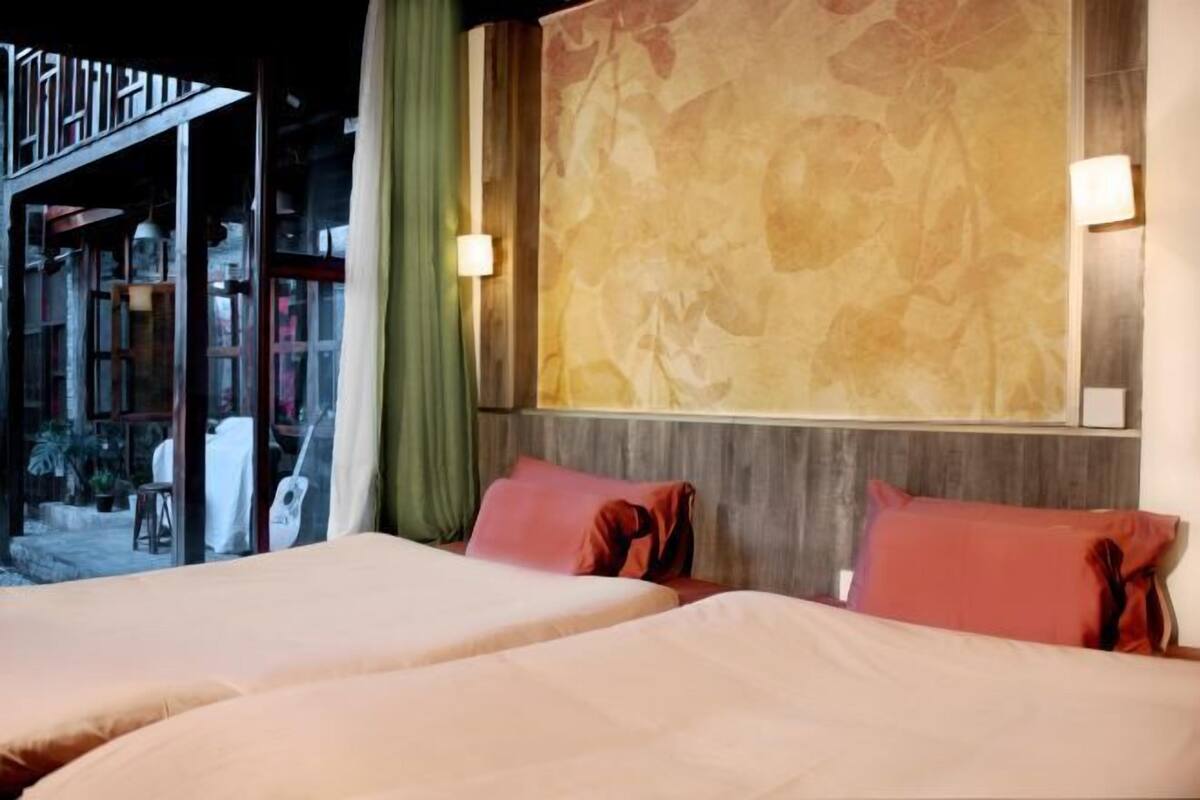 A hotel room with two beds, a large wall-mounted artwork, and a view of the outside.