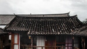 A traditional building with a tiled roof and wooden balcony. - FullMoon Inn (Lijiang)