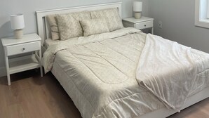 A bedroom with a bed, two bedside tables, a lamp, and a window.