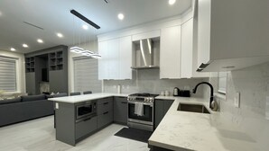 A modern kitchen with a central island, built-in oven, and stainless steel appliances.