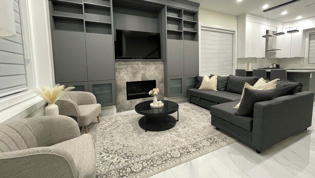 A modern living room with grey sofas, a black coffee table, and a fireplace.