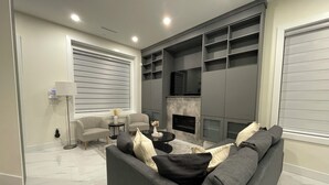 A modern living room with a grey sofa, two armchairs, a coffee table, and a fireplace.