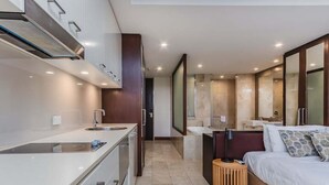Une chambre d’hôtel moderne dotée d’une kitchenette, d’un grand lit, d’une table de chevet et d’une salle de bain avec un grand miroir.