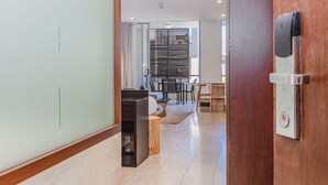 Un intérieur moderne avec une porte en bois, un coin repas et une cuisine en arrière-plan.