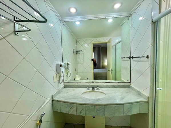 Un baño con un espejo grande, un lavamanos y una zona de ducha.