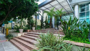 A modern building with a glass facade, outdoor stairs, and various potted plants. - LFlats Hotel Oscar Freire Hosp. Clínicas (São Paulo)