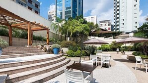 A courtyard with outdoor seating, steps leading to a covered area, and modern buildings in the background. - LFlats Hotel Oscar Freire Hosp. Clínicas (São Paulo)