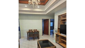 Una sala de estar con una mesa de comedor, sillas, un mueble para la televisión y un ventilador.