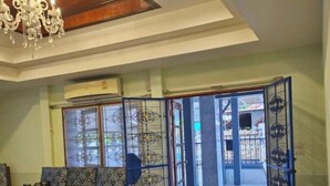 Un comedor con mesa y sillas de madera, un sofá y una araña.
