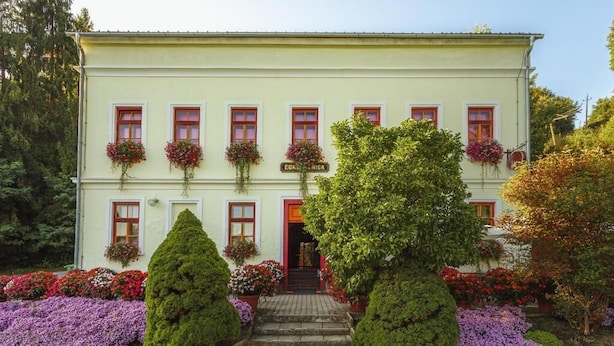 A two-story building with a symmetrical facade, multiple windows with red frames, and a central entrance. - Glorija Riverside Retreat Near Olimje (kozje)