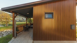 A wooden building with a covered patio area featuring outdoor seating. - Glorija Riverside Retreat Near Olimje (kozje)